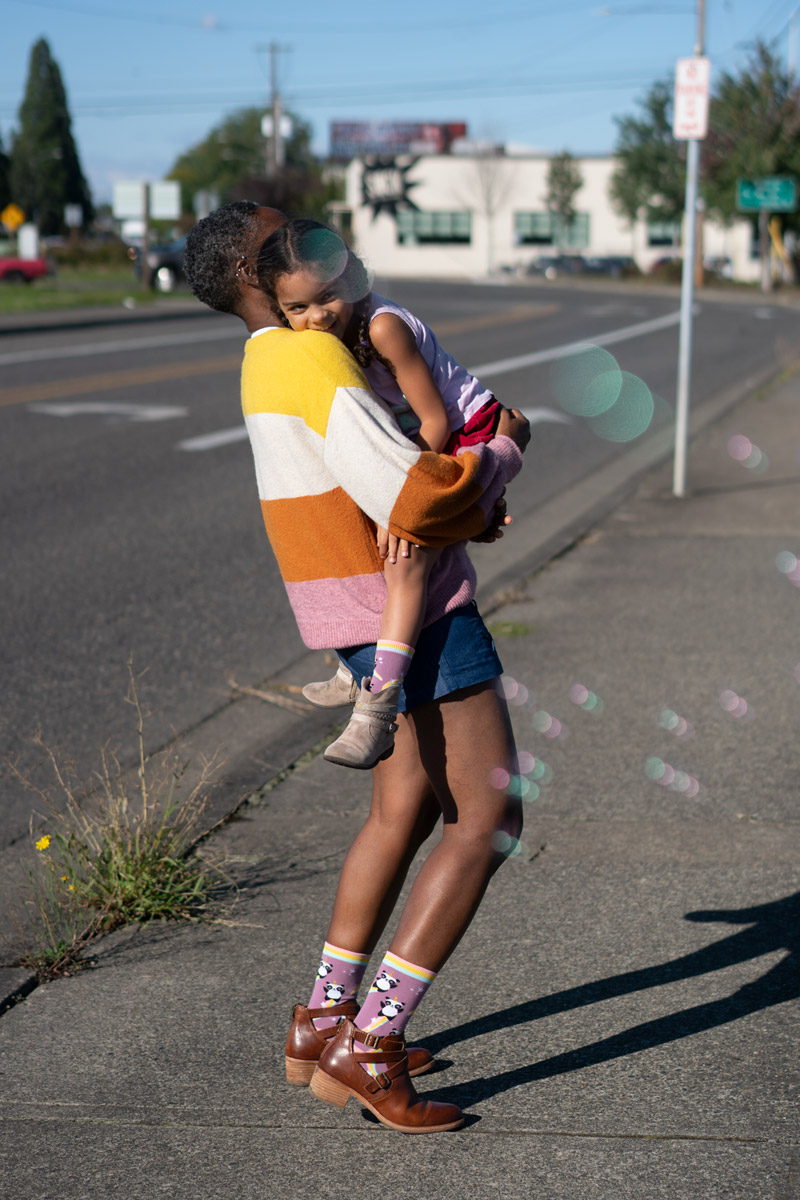 A mom holding her child from a low perspective. There is bokeh from bubbles surrounding them.